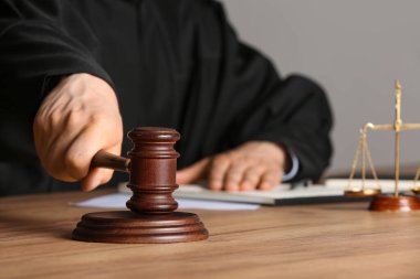 Tokmaklı erkek yargıç, adalet terazisi ve bürodaki belgeler.