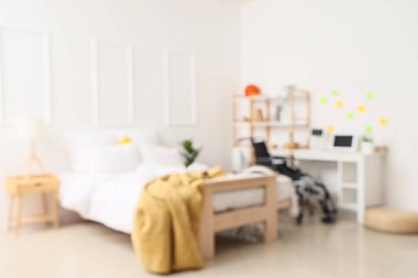 Tekerlekli sandalyesi ve masası olan öğrencinin yatak odası bulanık görünüyor.