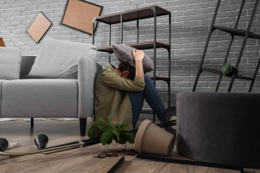 Deprem sırasında kanepede oturan yastıklı genç kadın.