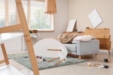 Kanepesi, masası ve raf ünitesi olan dağınık bir oturma odası.