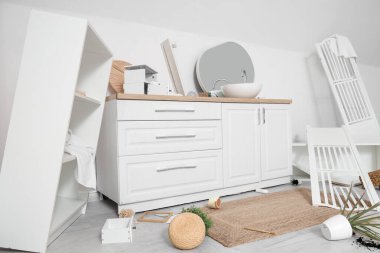 Ters çevrilmiş raf ünitesi ve dağınık banyodaki katlama ekranlı tezgahlar.