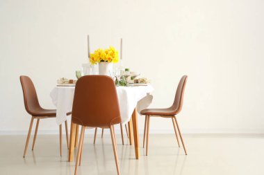 Beautiful table setting with daffodils and candles for wedding celebration in room