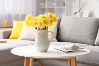 Oturma odasındaki kahve masasındaki sürahide nergis çiçeği