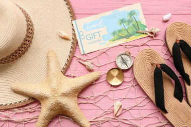 Seyahat hediye çeki, plaj aksesuarları ve ahşap arka planda balık ağı içeren kompozisyon