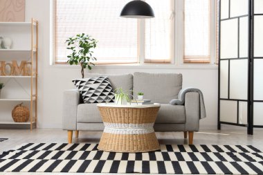 Gri kanepesi, sehpası, lambası ve raf ünitesi olan şık bir oturma odası.