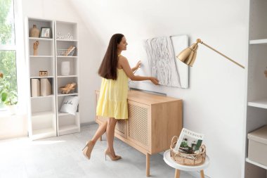 Evdeki ışık duvarına 3 boyutlu resim asan genç bir kadın.