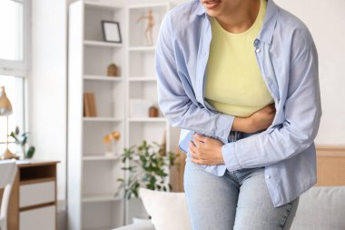 Evde adet sancısı çeken genç bir kadın, yakın çekim.