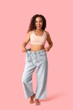 Pembe arka planda bol kotlu mutlu Afro-Amerikan kadın. Kilo verme konsepti