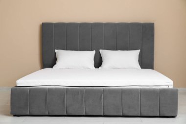 Yeni ortopedik yatak, odadaki bej duvarın yanındaki şık yatakta.