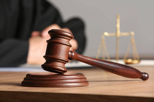 Молоток судьи на столе против адвоката-мужчины в офисе