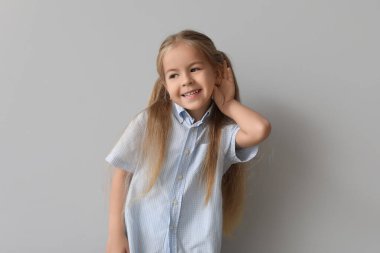 Gri arka planda işitme sorunu olan mutlu küçük kız.