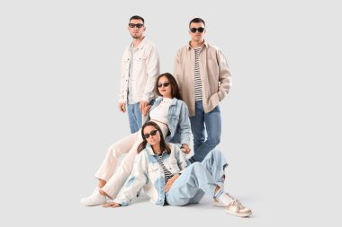 Beyaz arka planda şık kot giymiş bir grup genç.