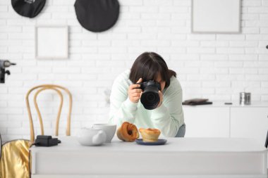 Stüdyoda kek fotoğrafı çeken kadın yemek fotoğrafçısı.