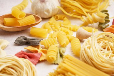 Açık arkaplanda farklı türde pişirilmemiş makarna, yakın plan