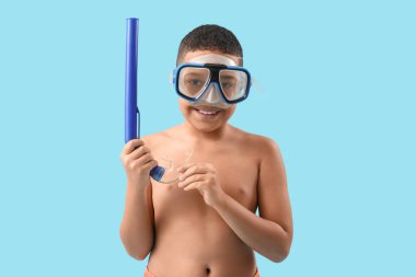 Mavi arka planda şnorkel maskesi olan Afro-Amerikalı bir çocuk.