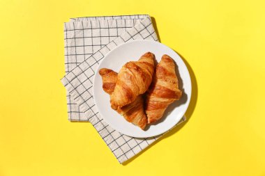 Sarı arka planda lezzetli kruvasan tabağı.