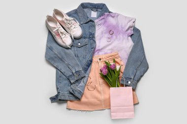 Beyaz arka planda kot ceketli, etekli, ayakkabılı, aksesuarlı ve laleli