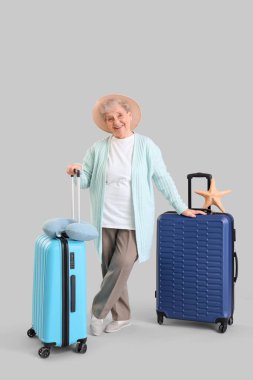 Kıdemli bayan turist bavulları ve deniz yıldızları açık arkaplanda