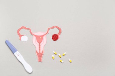 Gri arka planda haplı kağıt rahim ve hamilelik testi.