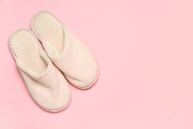 Pembe arka planda beyaz yumuşak terlikler. Üst görünüm