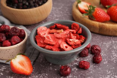 Dondurulmuş çilekli kase ve gri arka planda kirazlar