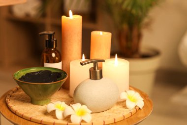 Koyu kaplıca salonundaki masada çamurlu ve yanan mumlarla kaplıca kompozisyonu, yakın plan.