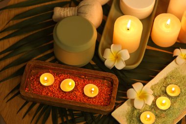 Salondaki masada yanan mumlar, deniz tuzu ve çiçekli spa kompozisyonu, yakın plan.