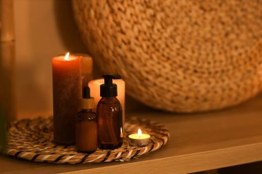 Kaplıca salonundaki raflarda yanan mumlar olan kozmetik şişeleri, yakın plan.