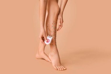 Modern epilatör ve bej arka planda renkli serpiştirilmiş güzel bir genç kadın. Yakın plan. Yasaklama kavramı