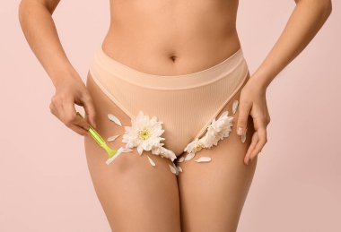 Pembe arka planda jileti ve çiçekleri olan güzel genç bir kadın, yakın plan. Yasaklama kavramı