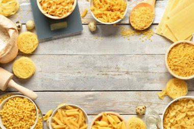 Farklı çiğ makarnadan yapılmış çerçeve ve ahşap arka planda mutfak aletleri.