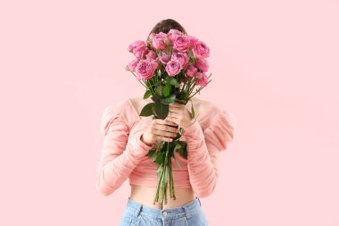 Pembe arka planda gülleri olan genç bir kadın.