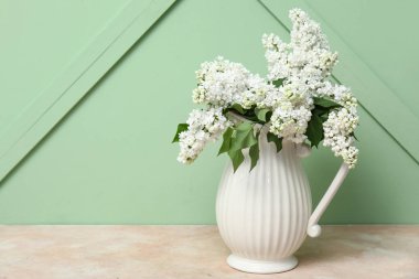 Masada yeşil arka planda güzel çiçek açan leylak sürahisi