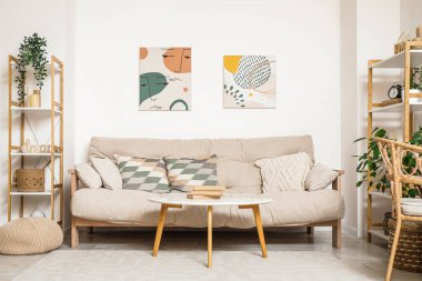 Kanepe, masa ve resimlerle aydınlık oturma odasının içinde.