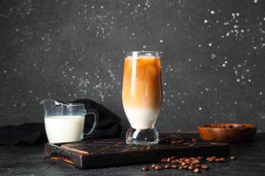 Kahve çekirdekli buzlu latte ve siyah arka planda bir sürahi süt.