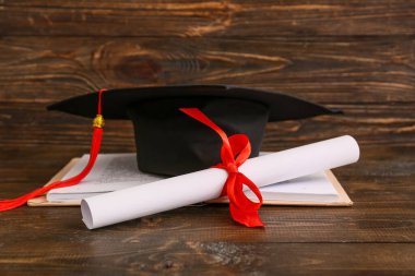 Ahşap zemin üzerine kitap ve harç tahtasıyla diploma
