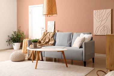 Gri kanepesi ve bej duvarın yanında kahve masası olan şık bir oturma odası.