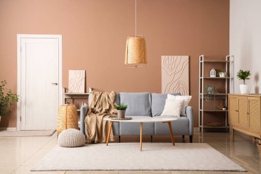 Gri kanepesi ve bej duvarın yanında kahve masası olan şık bir oturma odası.