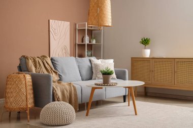 Gri kanepesi ve bej duvarın yanında kahve masası olan şık bir oturma odası.