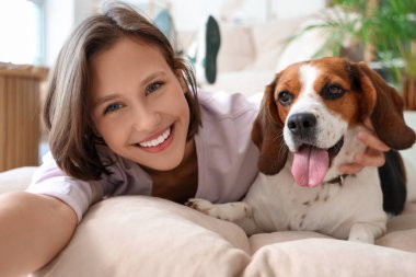 Beagle köpeği olan genç bir kadın evde selfie çekiyor, yakın plan.