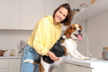 Mutfakta Beagle köpeği olan genç bir kadın.