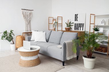 Oturma odasının içinde, kanepe ve dizüstü bilgisayarı olan bir masa.