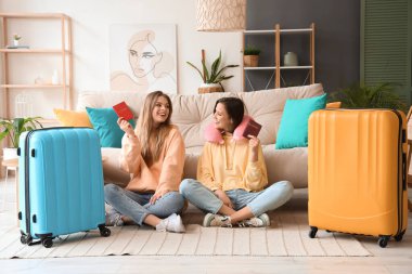 Pasaportları ve bavulları evde oturan bayan arkadaşlar.