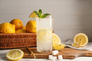 Beyaz ahşap arka planda naneli ve şekerli bir bardak taze limonata.