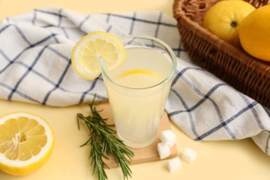 Sarı arka planda biberiye ve şekerli bir bardak taze limonata.