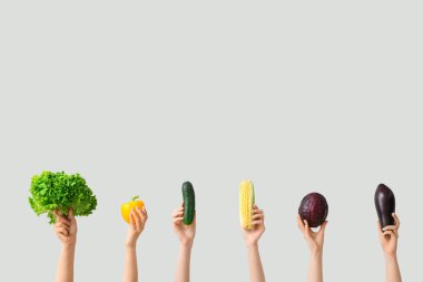 Female hands holding fresh vegetables on grey background