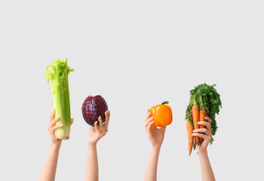 Female hands holding fresh vegetables on grey background