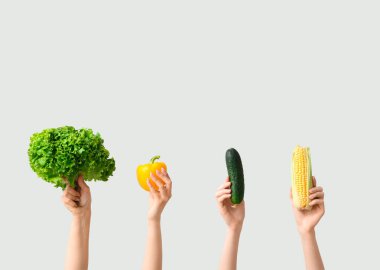 Female hands holding fresh vegetables on grey background