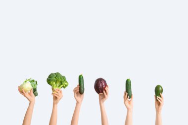 Female hands holding fresh vegetables on white background