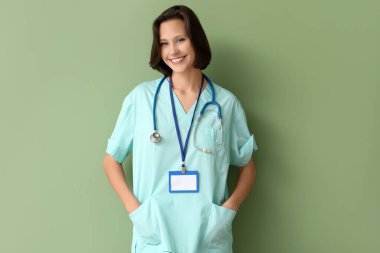 Rozeti ve steteskopu yeşil arka planda olan güzel bir kadın doktor.